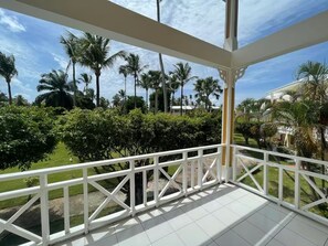 A balcony with a white railing, overlooking a well-maintained garden with palm trees and shrubs. - Condominio a solo unos pasos de la hermosa playa con gran piscina!! (Las Terrenas)