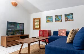 A living room with a television, sofa, coffee table, and artwork on the wall. - Condominio a solo unos pasos de la hermosa playa con gran piscina!! (Las Terrenas)