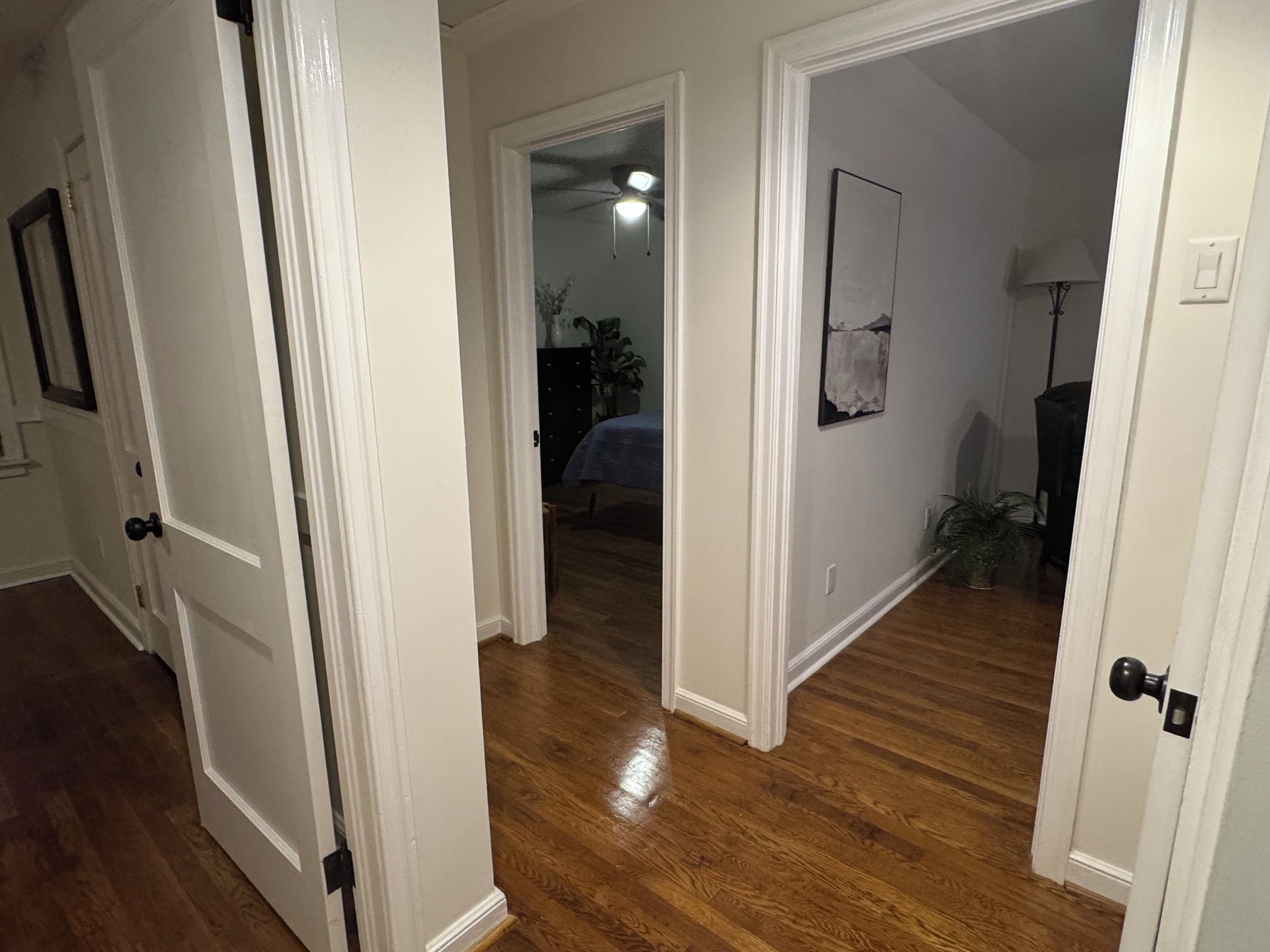 Ein Flur mit Holzboden, der zu einem Schlafzimmer mit Bett und Kommode führt.