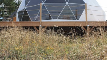 Una estructura de domo geodésico con una terraza de madera al frente.