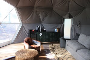 Een tent van binnen met een bank, een stoel, een kast en een televisie.