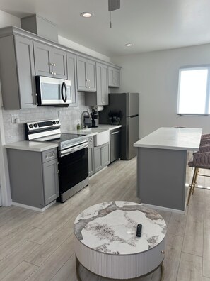 A modern kitchen with grey cabinetry, stainless appliances, and a marble coffee table. - Tranquil 1-bedroom house in beautiful Capitola near the beach (Capitola)