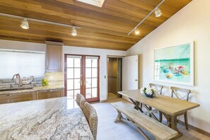 Une cuisine moderne dotée d’un plan de travail en marbre, d’un plafond en bois et d’un coin repas avec une table et un banc en bois.