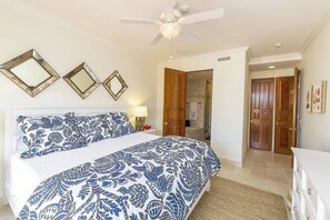 Une chambre à coucher avec un lit, un ventilateur de plafond et une porte donnant sur une salle de bain.