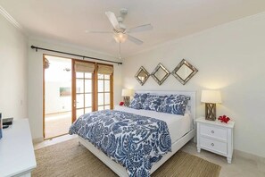 A bedroom with a bed, bedside tables, a ceiling fan, and a sliding glass door leading to an outdoor area. - Luxury Ocean-View 2-bedroom Condo Across from Beach (Redondo Beach)