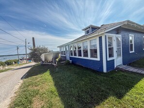 A single-story house with a covered porch, a boat in the driveway, and a view of the water. - A working waterfront cottage in Downeast Maine, trails and beaches nearby (Jonesport)