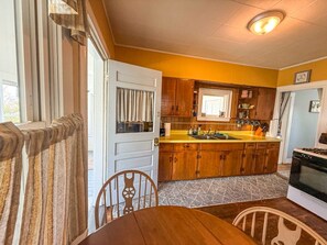 Une cuisine compacte avec des meubles en bois, un îlot central et un coin repas comprenant une table et des chaises.