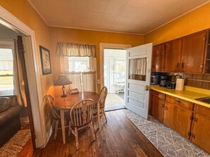 A compact kitchen with wooden cabinets, a dining table with chairs, and a view to the outside. - A working waterfront cottage in Downeast Maine, trails and beaches nearby (Jonesport)