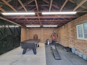 A gym with a pool table, exercise equipment, and weightlifting benches.