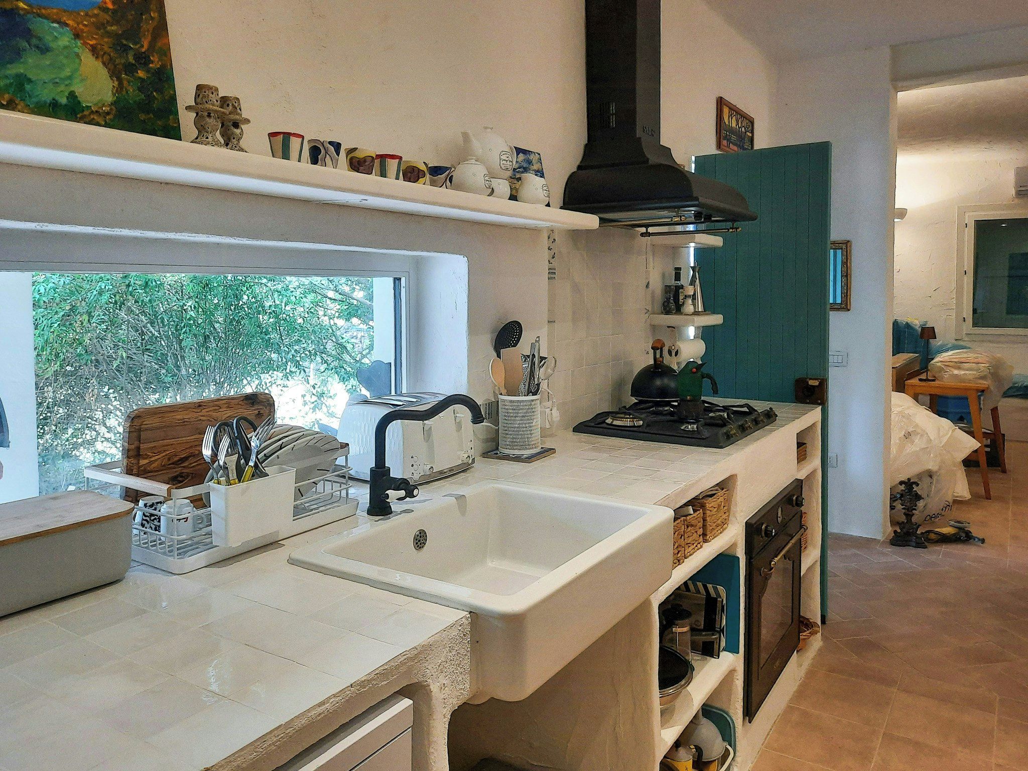 A kitchen with a window, white countertops, a sink, and a stove.