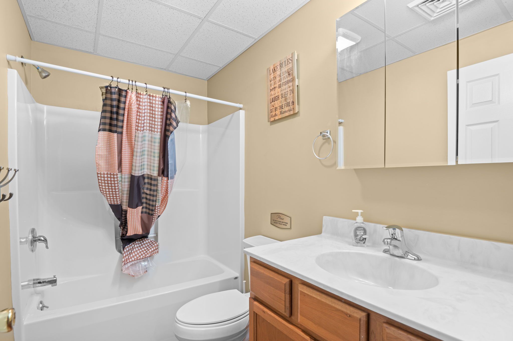A bathroom with a bathtub, toilet, vanity with a sink, and a shower curtain.