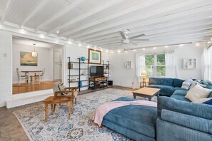 Un salon spacieux avec un grand canapé, un coin repas comprenant une table et des chaises en bois, et un téléviseur posé sur un meuble.