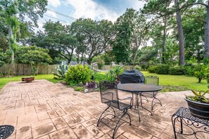Une terrasse avec une table et des chaises, entourée d’une clôture en bois et de verdure.