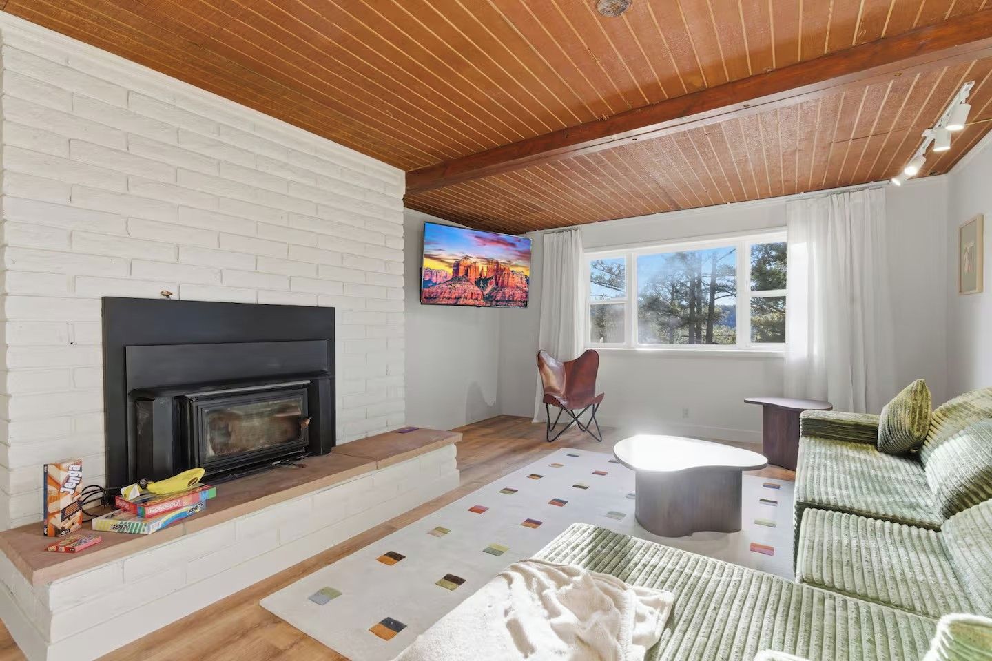 Una sala de estar con chimenea, un sofá, una mesa de centro y un ventanal con cortinas.
