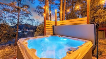 Un jacuzzi con cubierta de madera y vista a árboles y un paisaje lejano.