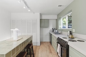 A modern kitchen with white cabinetry, a built-in oven, and a window providing natural light. - Armando 1 (Williams)
