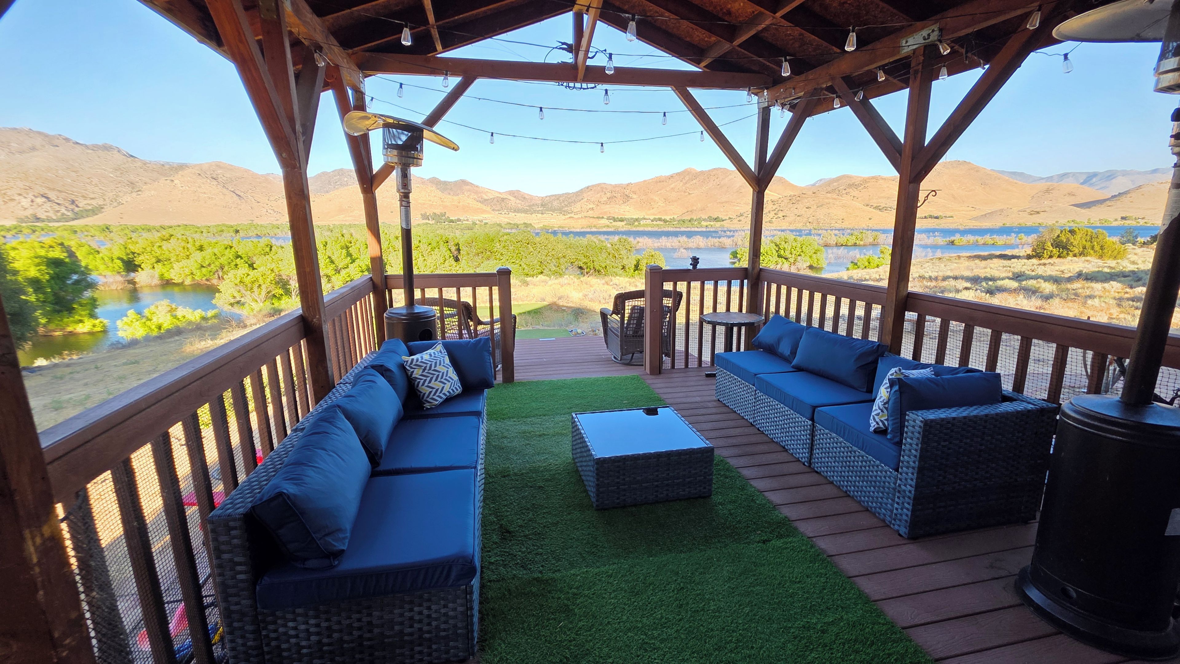 A covered outdoor seating area with a view of a lake and mountains.