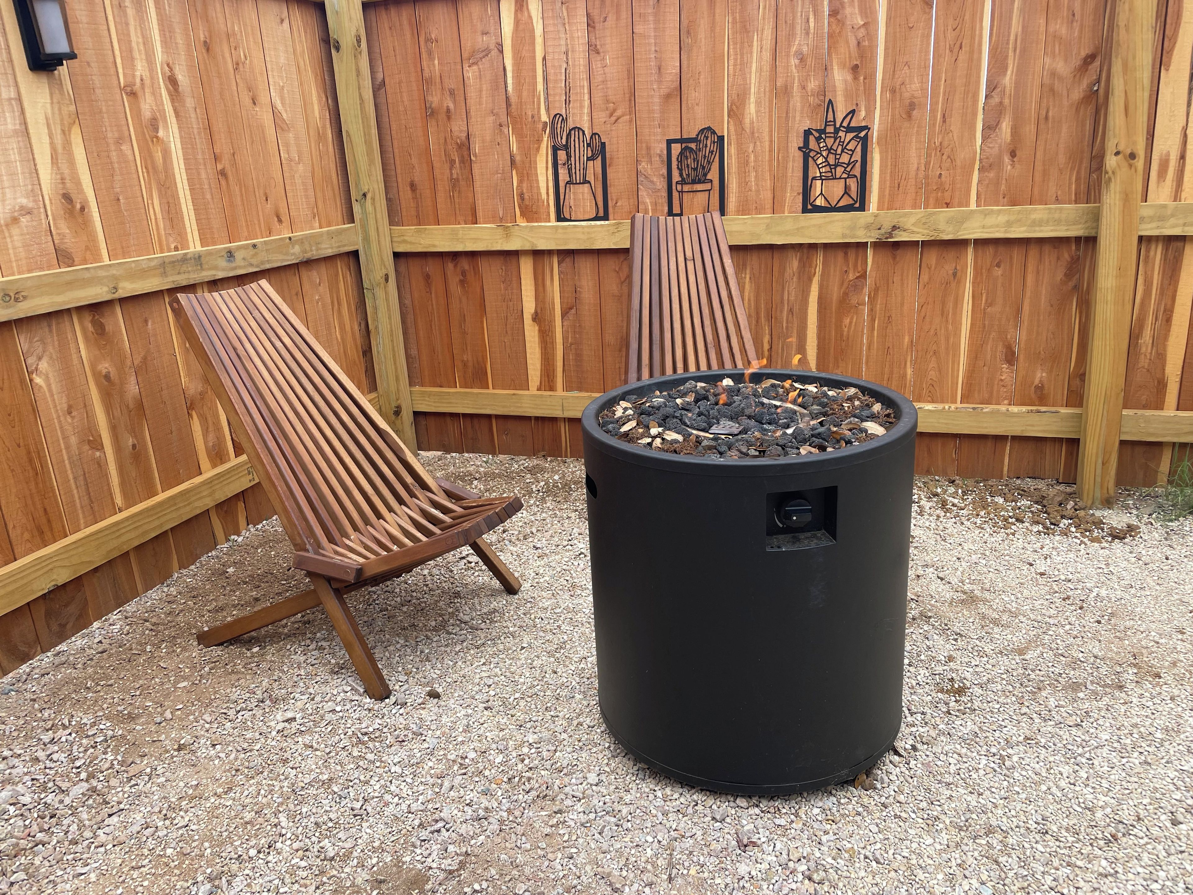 Eine Holzterrasse mit zwei Liegestühlen und einer schwarzen Feuerstelle.