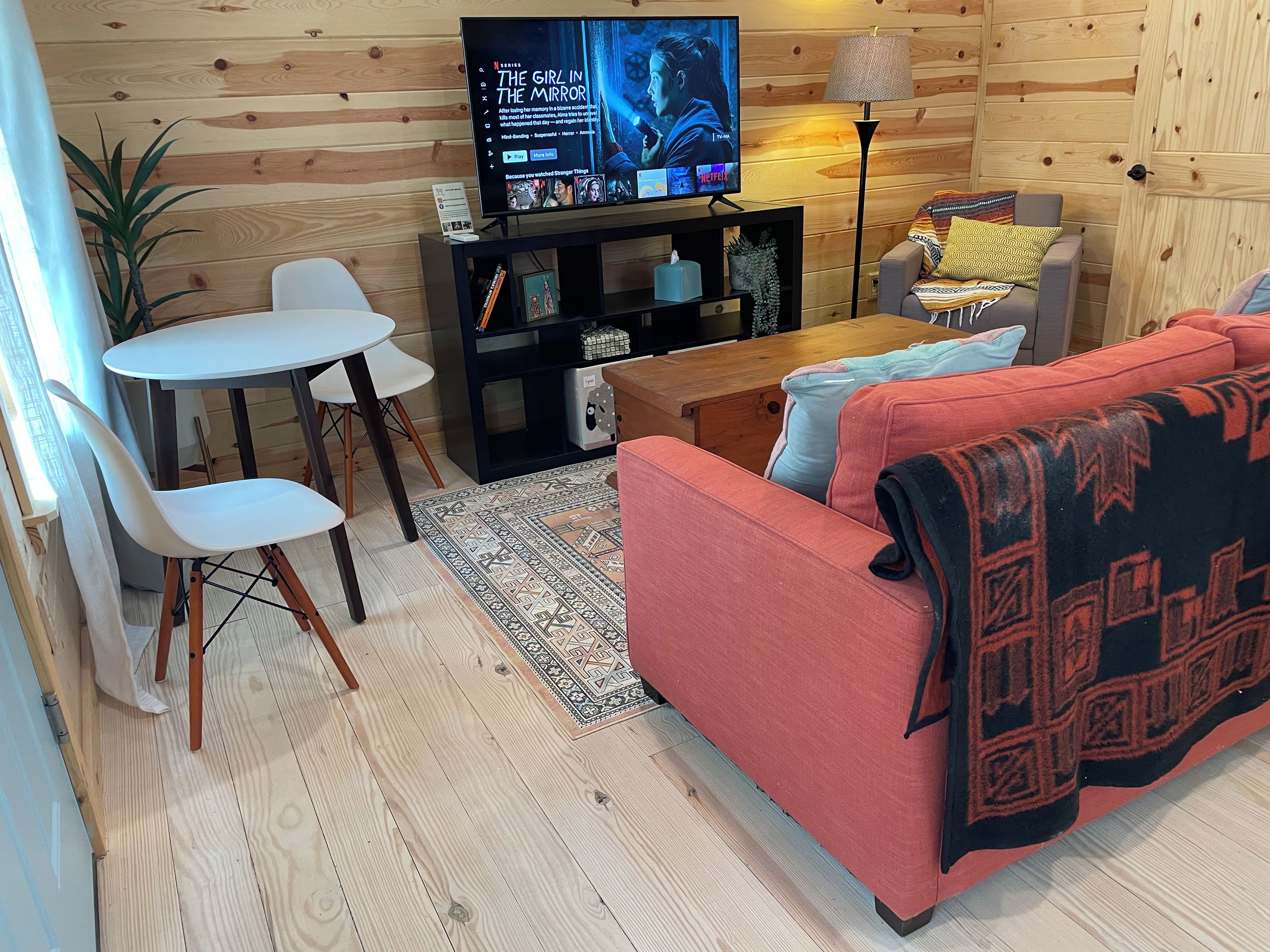 Ein gemütliches Wohnzimmer mit Fernseher, einer Couch, einem Couchtisch und einem Essbereich mit Stühlen.