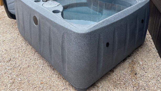 Un bain à remous de spa avec une terrasse en bois et une clôture en bois en arrière-plan.