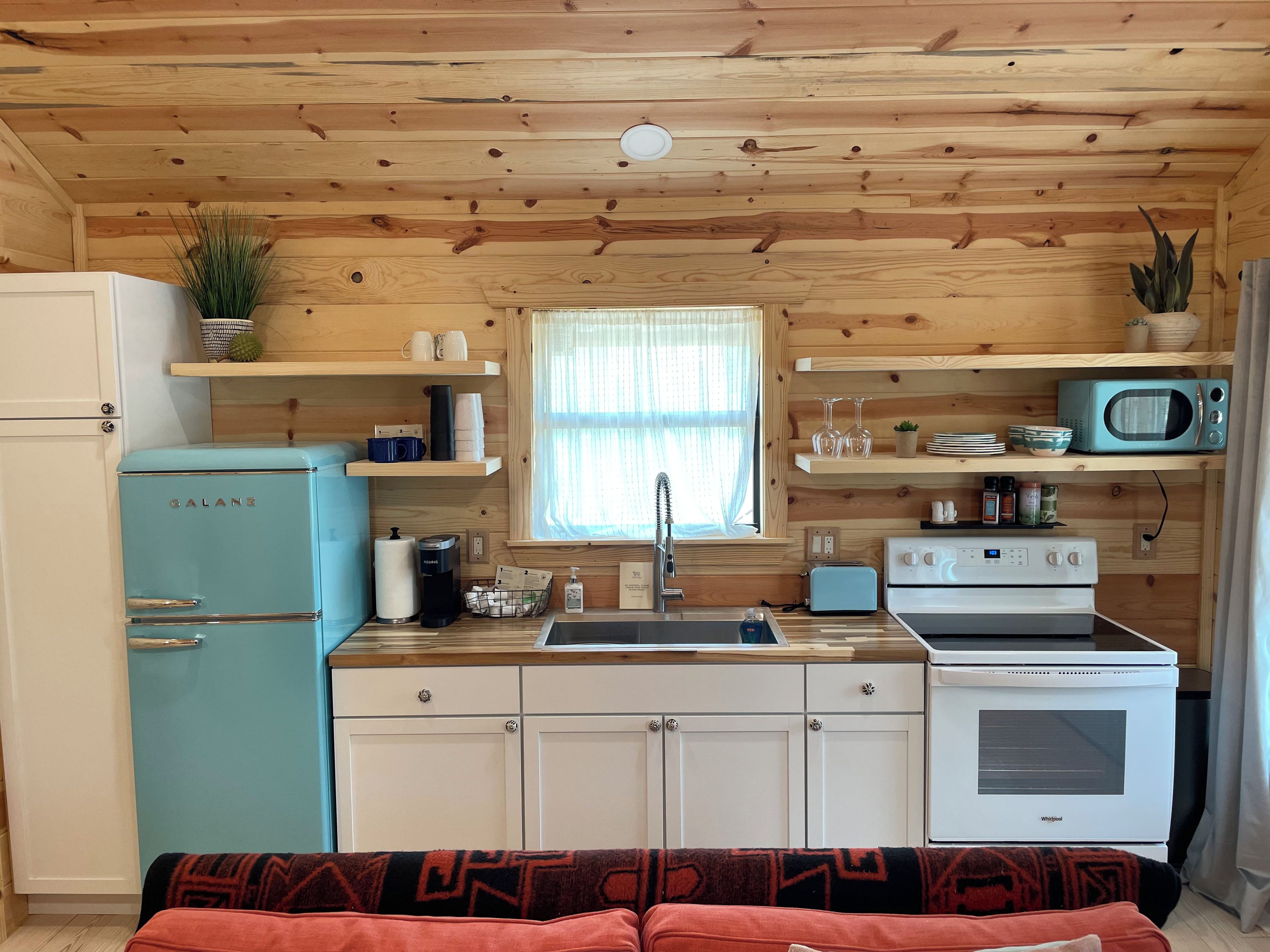 A compact kitchen with a refrigerator, microwave, toaster, and stove.
