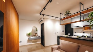 Una cocina moderna con horno integrado, un comedor con mesa y sillas, y una sala de estar con sofá.