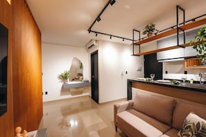 A modern kitchen with a built-in oven, a dining area with a table and chairs, and a living room with a sofa. - Blue Life Stay 111 (Anápolis)