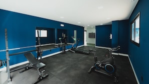 Un gimnasio con equipo de ejercicio, una banca y un espejo grande.