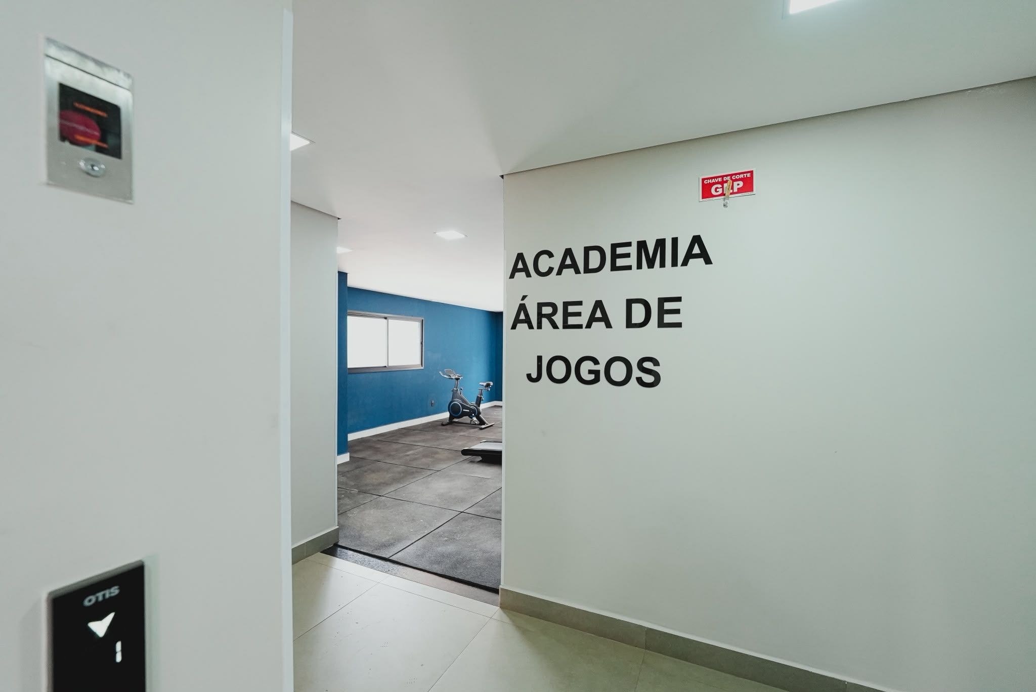 Un pasillo con un cartel que indica 'Academia Area of Games' y una pared azul al fondo.