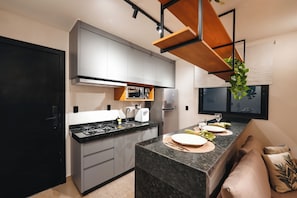 A modern kitchen with grey cabinets, a black countertop, and a built-in oven. - Blue Life Stay 111 (Anápolis)
