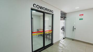 Käytävällä on lasiovi, jossa on kyltti, jossa lukee ”COWORKING”, ja toinen kyltti, joka osoittaa uloskäynnin.