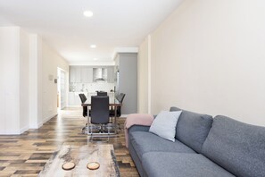 A modern living room with a grey sofa, a wooden coffee table, and a dining area with a table and chairs. - TenoHomes Spacious Buenavista House & BBQ (Buenavista del Norte)