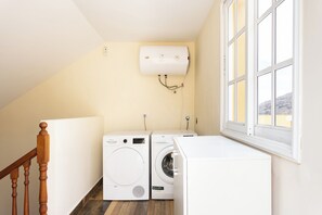 A laundry room with two washing machines, a dryer, and a water heater mounted on the wall. - TenoHomes Spacious Buenavista House & BBQ (Buenavista del Norte)