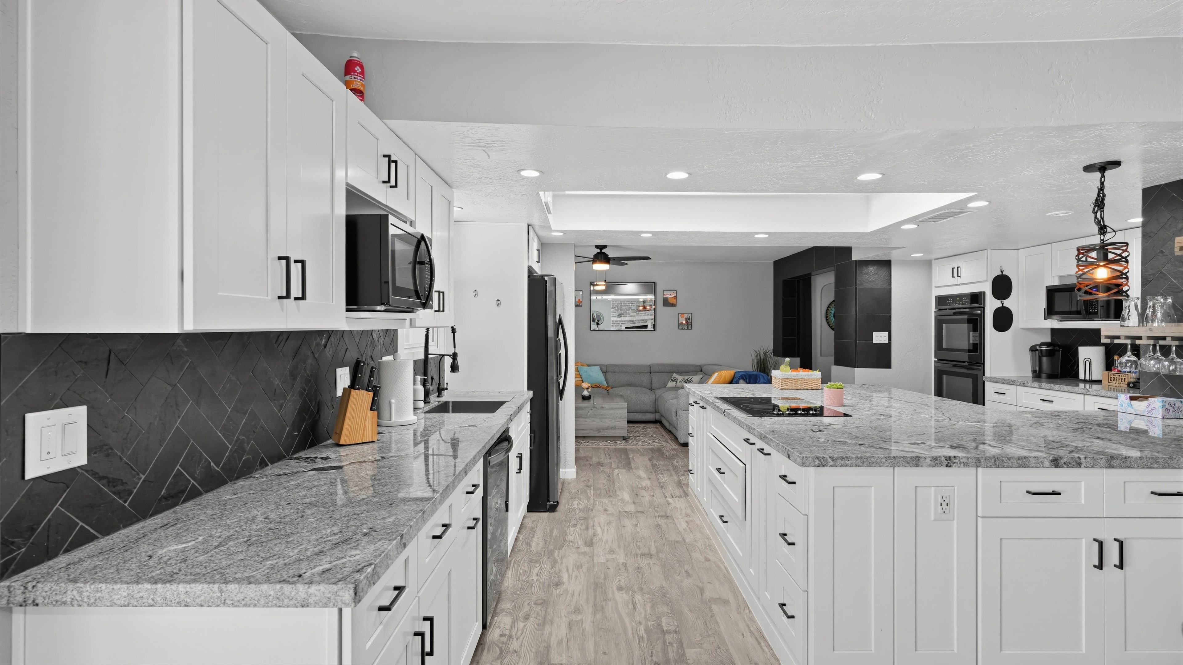 A modern kitchen with white cabinetry, granite countertops, and a central island.