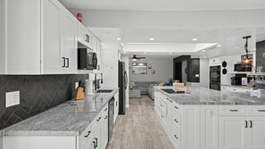 Une cuisine moderne avec des meubles blancs, des plans de travail en granit et un îlot central.