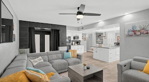 Un salon moderne avec un canapé gris, une table basse et un ventilateur de plafond.