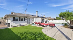 Il s’agit d’une propriété r ésidentielle dotée d’une piscine, d’une terrasse avec des chaises longues rouges et d’une pelouse bien entretenue.