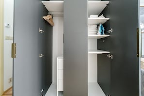 A modern closet with white shelves, a hanging rack, and a small drawer unit. - Blueground | Vinohrady, view, nr park &  Náměstí Míru (PRG-112) (Prague)