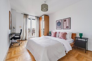 Ein modernes Schlafzimmer mit einem großen Bett, einem Schreibtisch und Blick auf die Stadt.