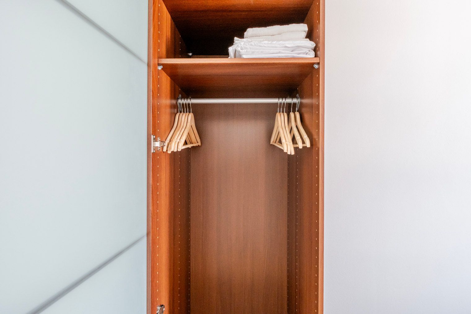 Ein Holzschrank mit Kleiderstange und gefalteten Handtüchern darauf.