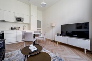 Ein modernes Wohnzimmer mit Küche, Essbereich und Flachbildfernseher.