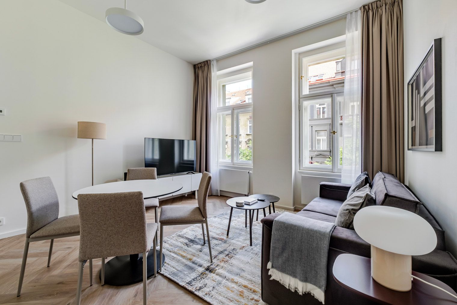 A modern living room with a dining area, a flat-screen TV, and a sofa.