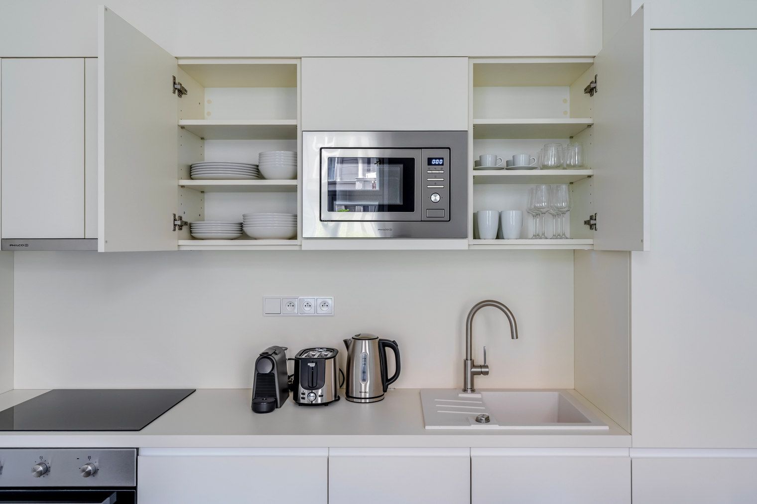 Una cocina moderna con microondas integrado, hervidor, tostadora y pileta.