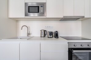 Eine moderne Küche mit integriertem Mikrowellenherd, Wasserkocher, Toaster und Herd.