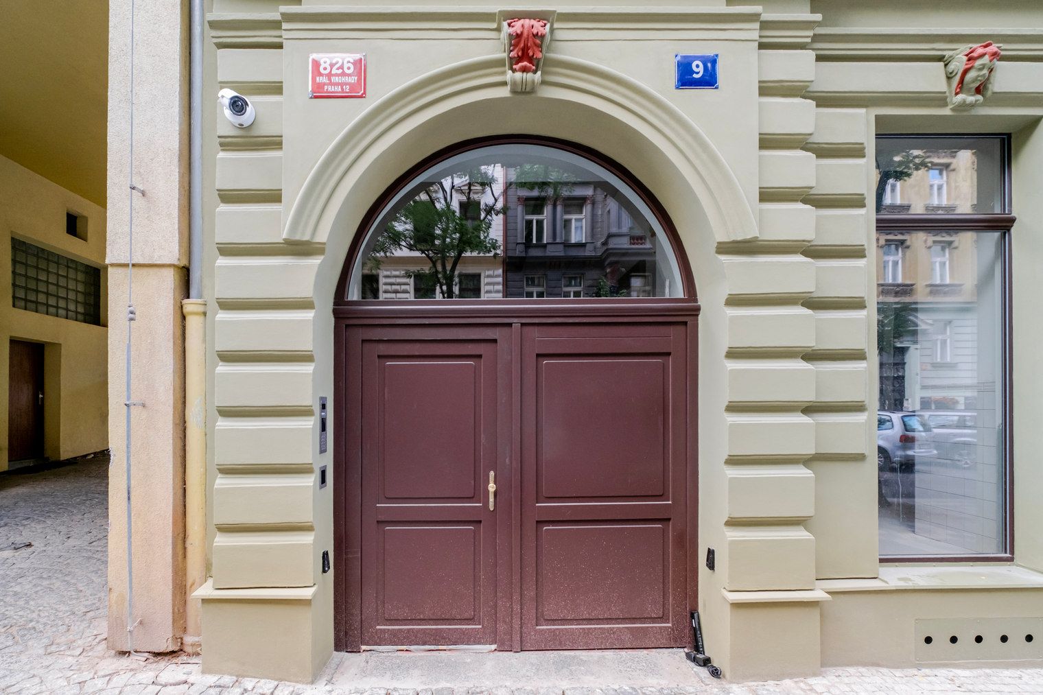 Ingresso di un edificio con una porta doppia, una telecamera di sicurezza e un cartello con il numero civico.