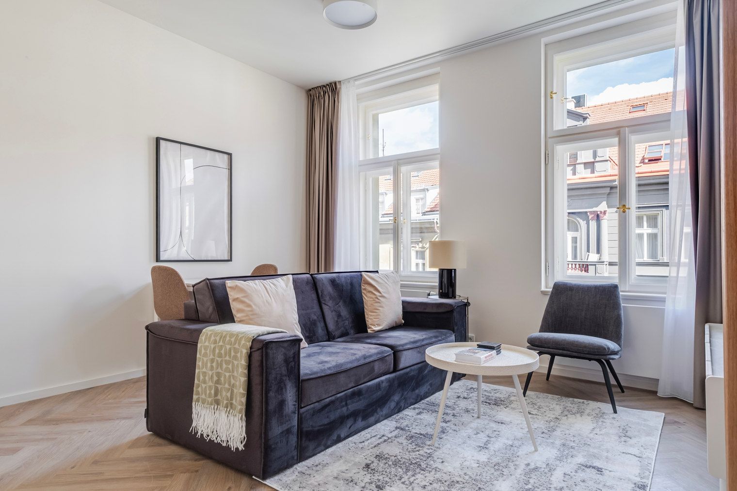 A modern living room with a sofa, a chair, a small table, and a window with curtains.
