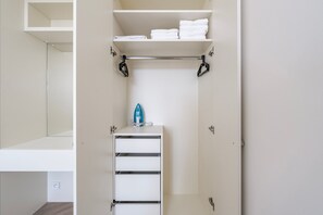 A walk-in closet with shelves, a hanging rack, and a storage unit. - Blueground | Vinohrady, view, nr Riegrovy Sady (PRG-124) (Prague)