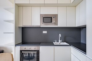 A modern kitchen with a built-in microwave, a gas stove, and a sink. - Blueground | Vinohrady, view, nr Riegrovy Sady (PRG-124) (Prague)