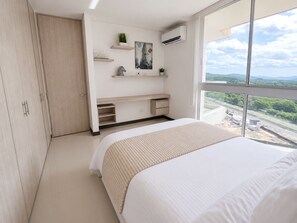 Ein Schlafzimmer mit Bett, Kleiderschrank, Schreibtisch und einem Fenster mit Blick.