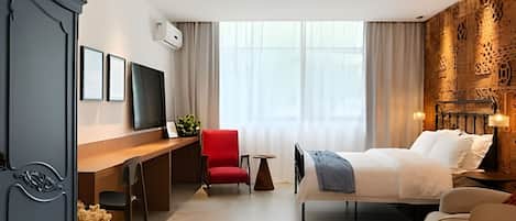 Habitación de hotel con cama, escritorio, silla, televisor y un adorno en la pared.